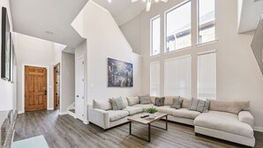 Ein geräumiges Wohnzimmer mit einem großen Ecksofa, einem Couchtisch und einem Stadtbild an der Wand.