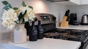 Una cocina con encimera blanca, estufa y dos botellas con las etiquetas "HUILE" y "VINEGA".