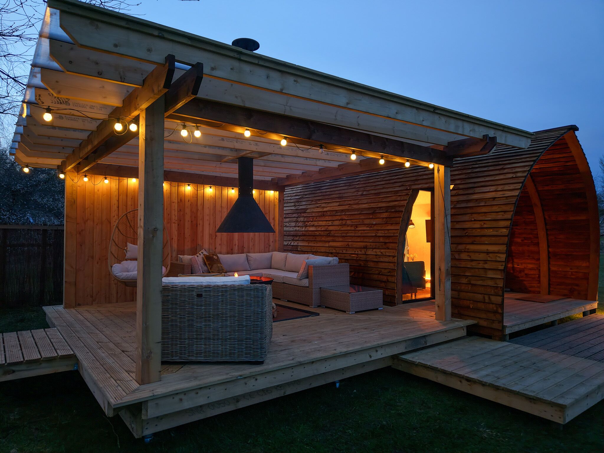 A wooden cabin with a covered porch, a hanging light fixture, and a fireplace.