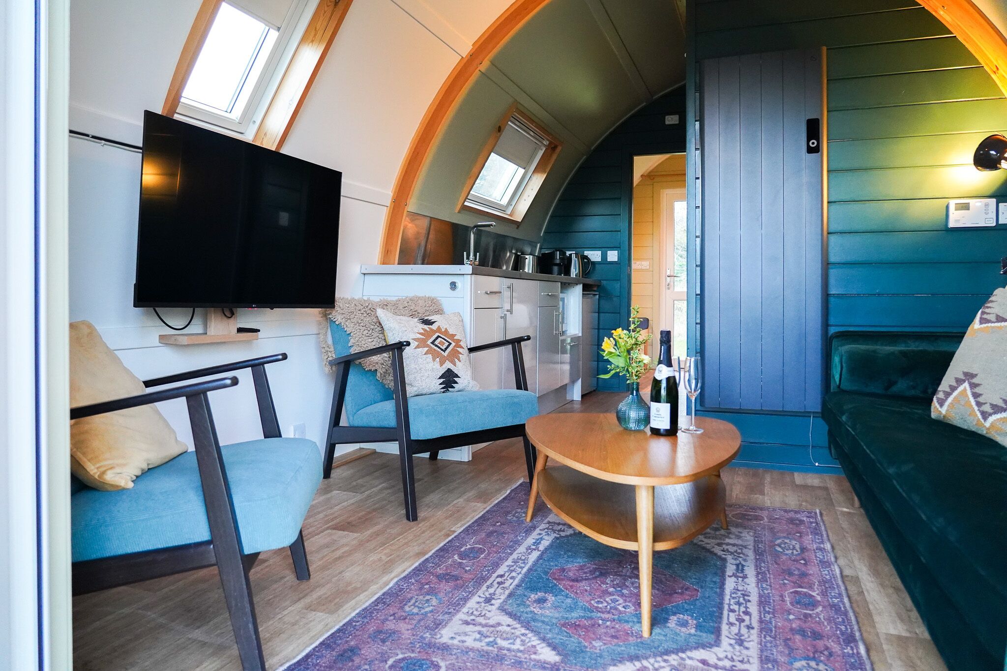 A compact living space with a TV, sofa, and a small kitchen area.