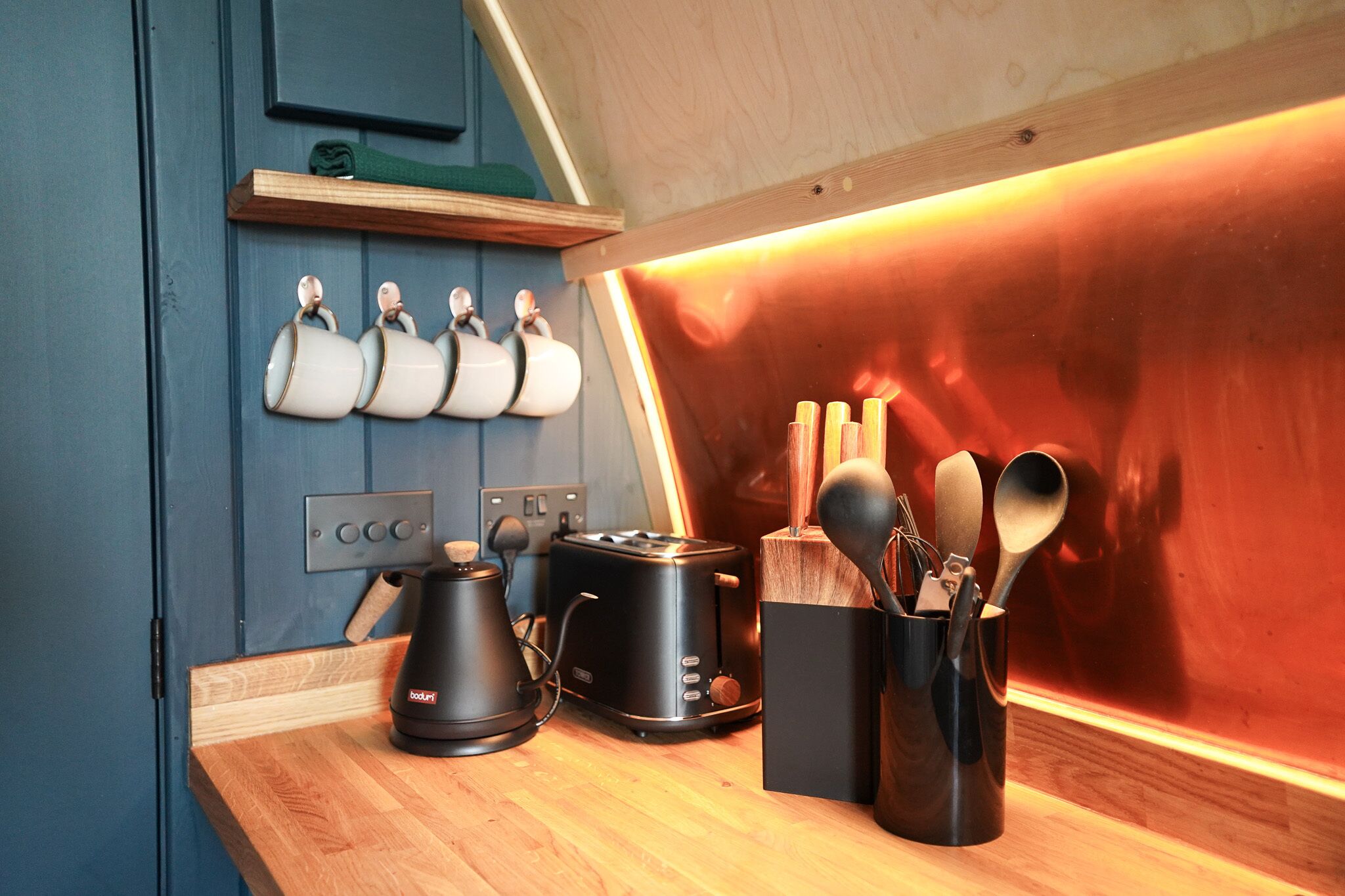 A kitchen with a toaster, kettle, and utensils on the counter.