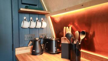 A kitchen with a toaster, kettle, and utensils on the counter.