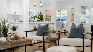 Un salon moderne avec des canapés blancs, des tables basses en bois et des luminaires suspendus.