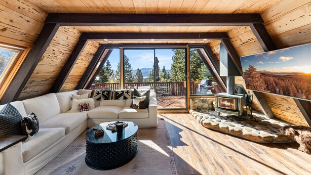 Ein gemütliches Wohnzimmer im Loft-Stil mit großem Fenster, Kamin und einer bequemen Sitzecke.