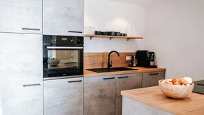 Una cocina moderna con horno empotrado, cafetera y encimera de madera.