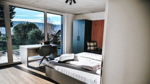 Un dormitorio moderno con una cama, un escritorio y vistas al exterior.