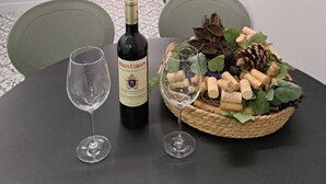 Un comedor con una mesa dispuesta para dos personas, que incluye una botella de vino, dos copas y un cesto de corchos.