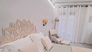 Un dormitorio con una cama grande, una silla y una mesita.