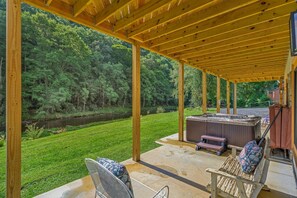 Alpendre coberto com hidromassagem, assentos e vista para uma área arborizada.