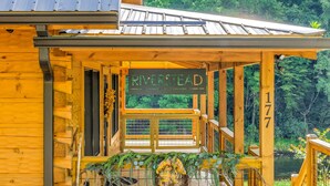 Een houten vakantiehuisje met een bord waarop 'RIVERSTEAD' staat en het nummer '177'.