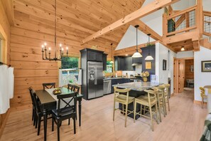 Una cocina amplia con una isla central, vigas de madera en el techo y electrodomésticos modernos.