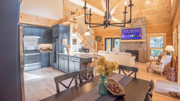 Un amplio espacio de sala con chimenea, una mesa de comedor con sillas y una cocina equipada con electrodomésticos modernos.