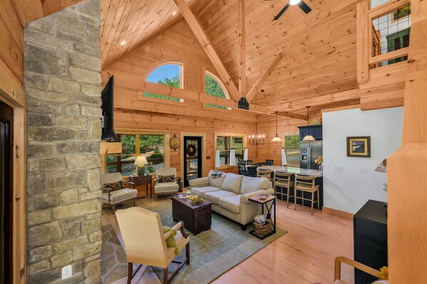 A spacious living area with a stone wall, wooden ceiling, and a large window.