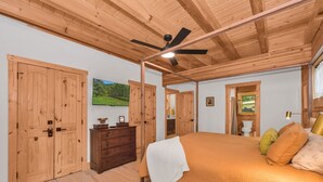 Een slaapkamer met een bed, een houten garderobe, een dressoir en een plafondventilator.