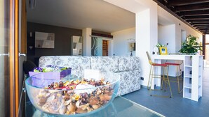 Una sala moderna con una mesa de centro de vidrio, un sofá floral y un comedor con una mesa y sillas blancas.