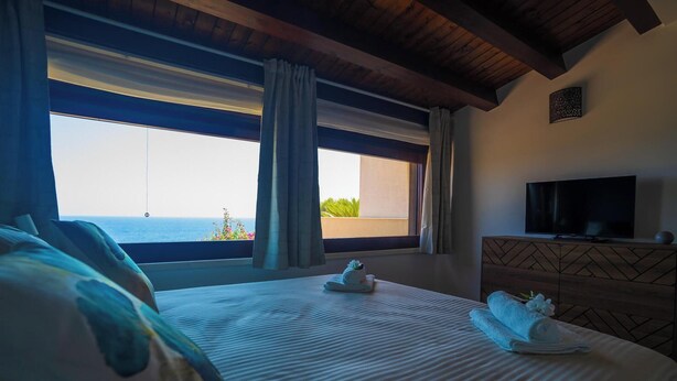 Una habitación de hotel con una cama grande, televisión y vista al mar.