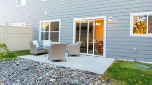 A house with a patio area featuring wicker furniture and a dining table.