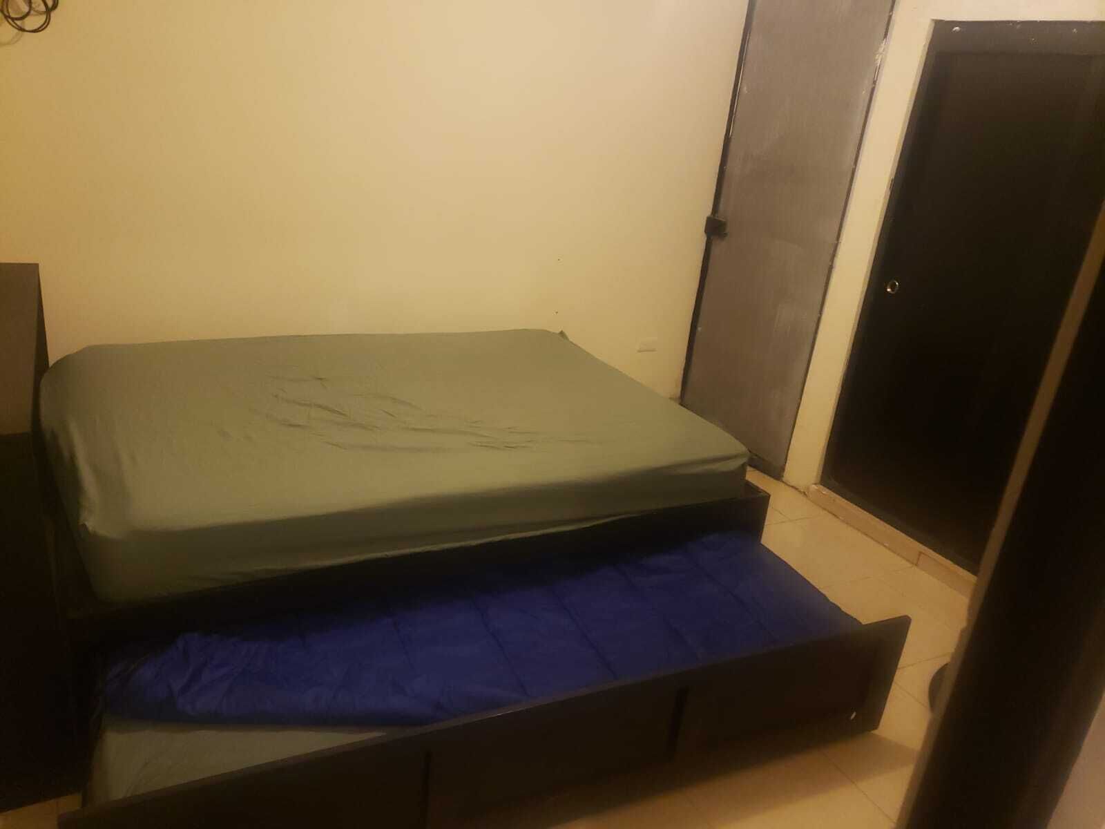 Una habitación pequeña con cama individual, colchón y una manta azul.