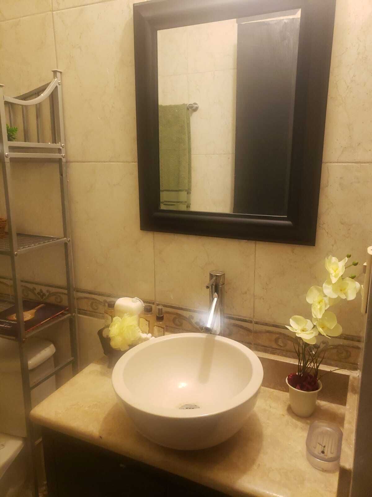 A bathroom with a white sink, a mirror, and a towel rack.