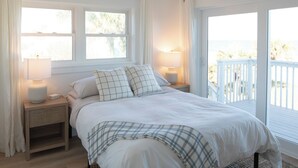 Ein Schlafzimmer mit einem Bett, Nachttischlampen, einem Deckenventilator, einem Fenster und einem Balkon.