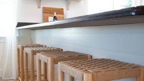 Eine Küche mit Holzschemeln, einer weißen Arbeitsplatte und Regalen mit Küchenutensilien.