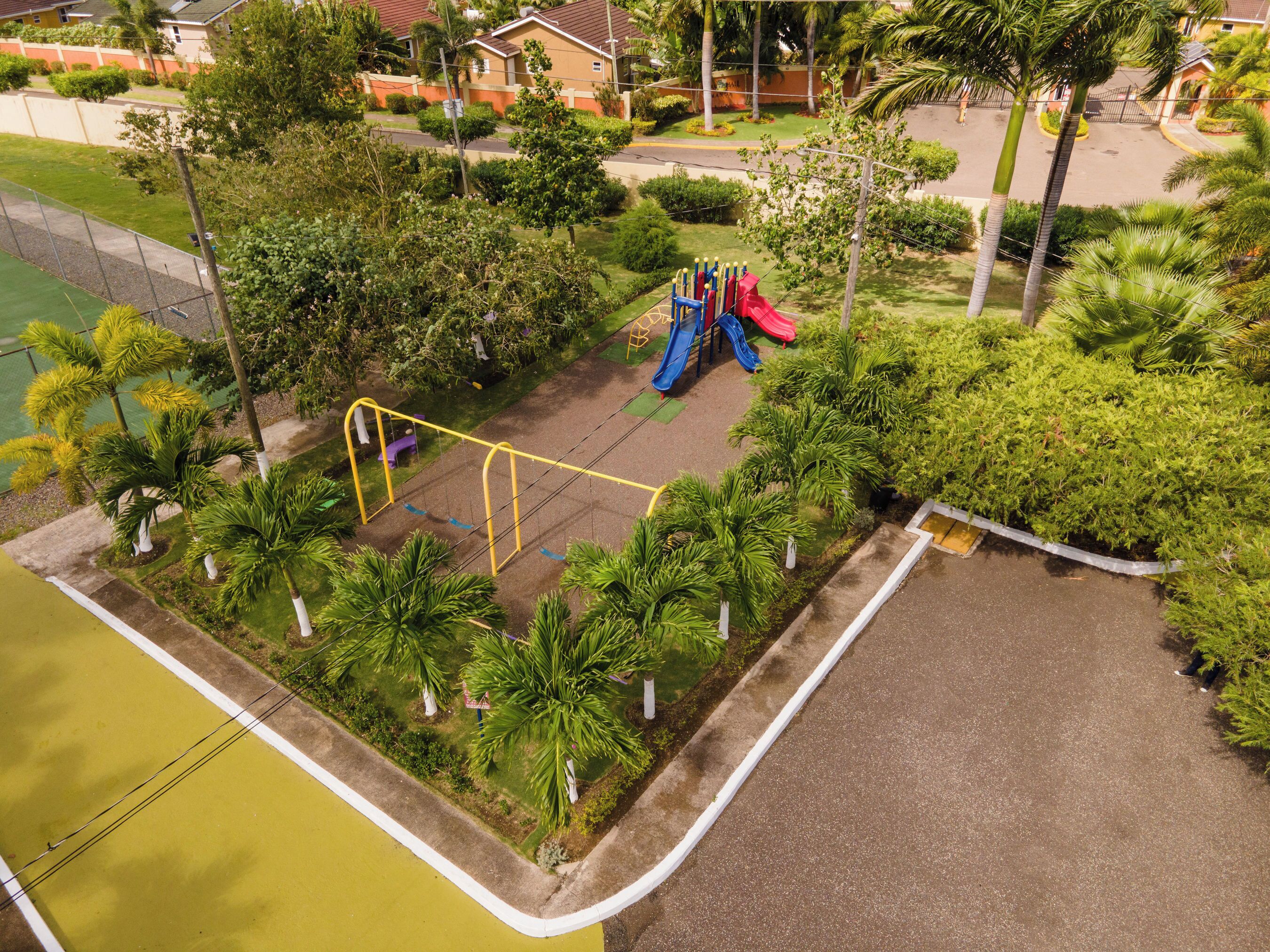 An aerial view of a playground with swings, a slide, and surrounding greenery.