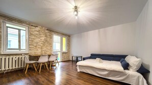 Ein Zimmer mit Holzboden, einem Bett mit blauer Kopfteil, einem weißen Heizkörper und einer Wand mit Steinmuster.