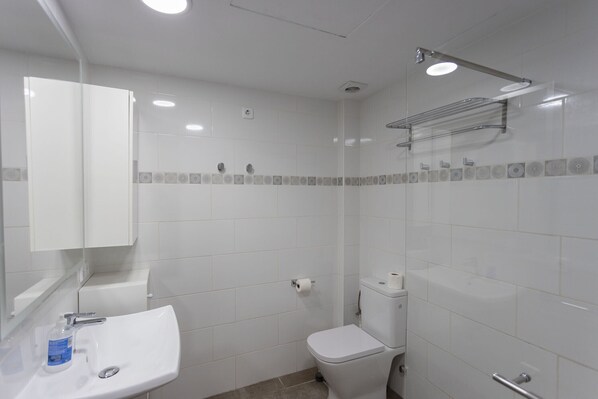 Une salle de bain avec un lavabo blanc, des toilettes et un espace douche.