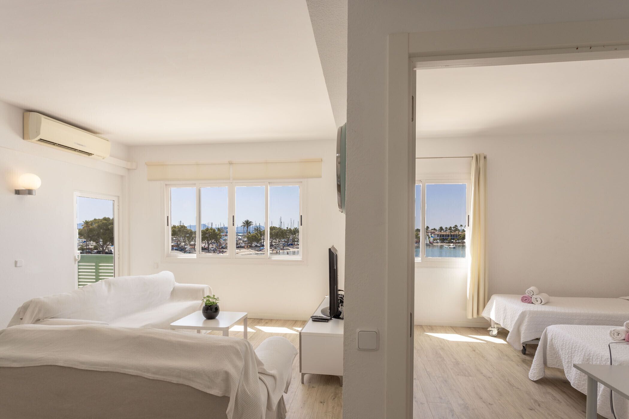 Habitación de hotel con cama, escritorio, televisor y vista al mar.