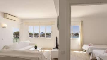 Habitación de hotel con cama, escritorio, televisor y vista al mar.