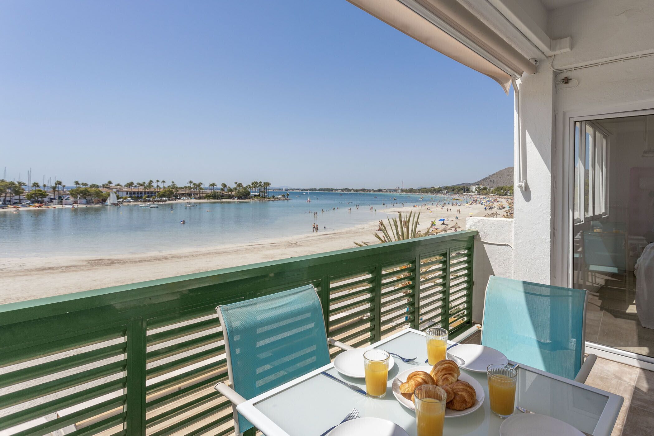 Balcón con mesa listo para el desayuno y vista a la playa.