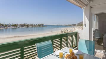 Balcón con mesa listo para el desayuno y vista a la playa.