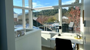 A modern room with large windows, a desk, and a chair.
