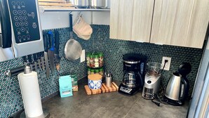 A kitchen with a coffee maker, a kettle, and a blender on the counter. There are also paper towels and a bag of coffee on the counter.