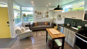 A modern living room with a sofa, a dining table, and a kitchen area with a stove and sink.