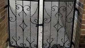 A wrought iron gate with intricate designs, set in a brick wall.