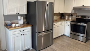 A modern kitchen with white cabinets, stainless steel appliances, and a wooden countertop.