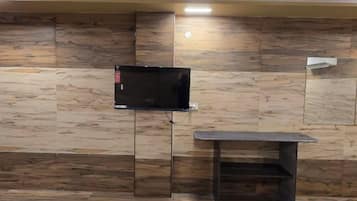A room with a television mounted on a wall, a small table, and a bench.