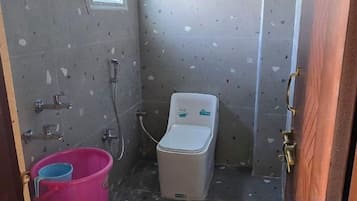 Un baño pequeño con inodoro, ducha y un balde.