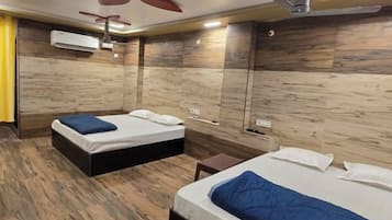 A hotel room with two beds, a ceiling fan, and a wooden floor.