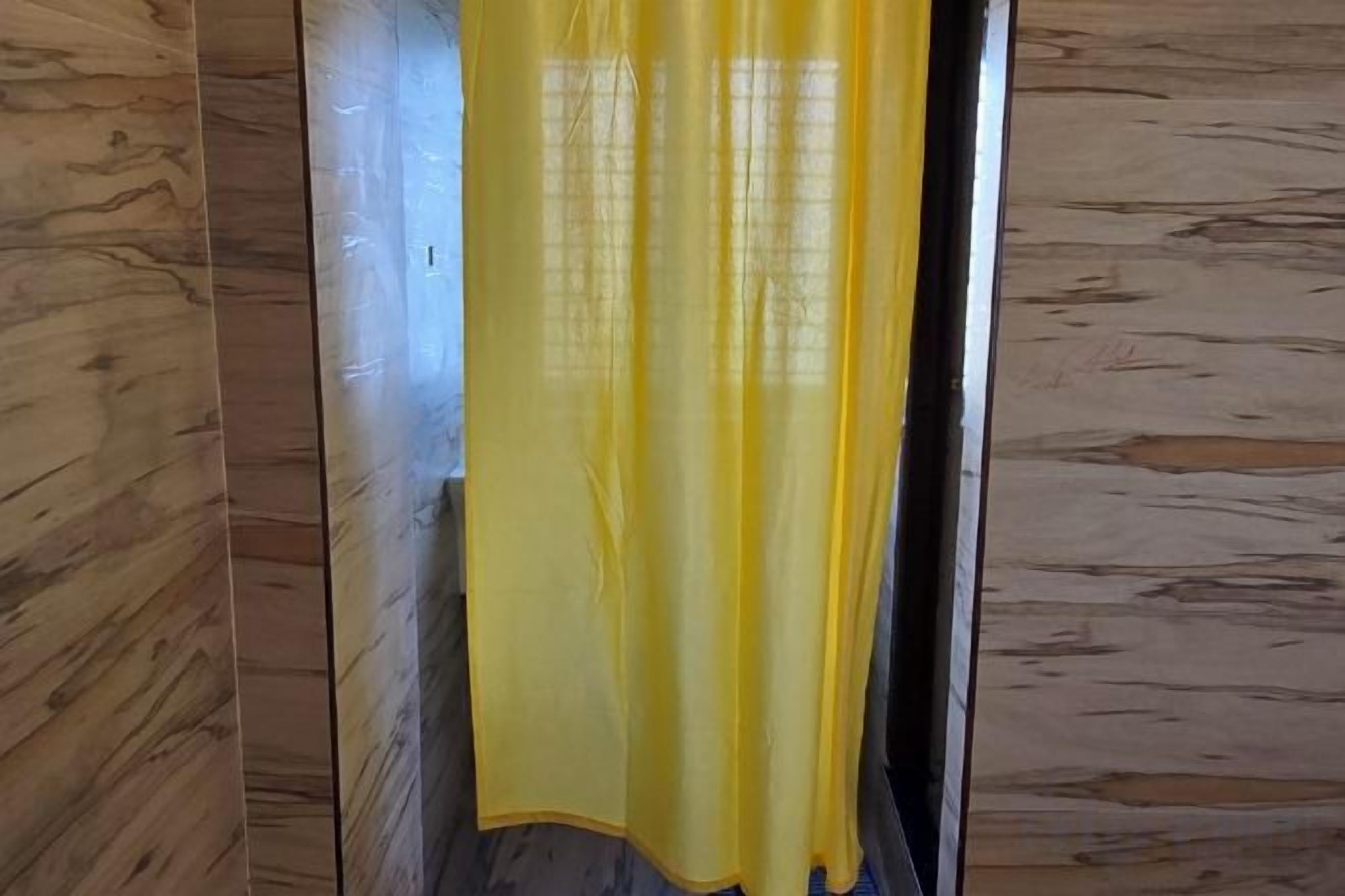 A room with wooden paneling and a yellow curtain.