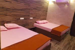 Une chambre avec deux lits, chacun agrémenté de draps roses et d’oreillers décoratifs orange.