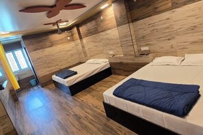Una habitación de hotel moderna con dos camas, un ventilador de techo y suelo de madera.