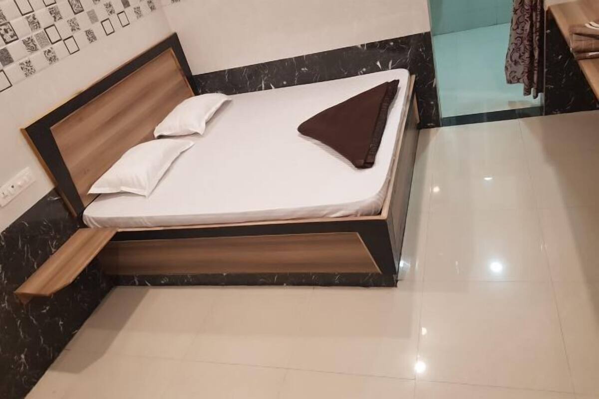 A bed with a wooden frame, white bedding, and a brown pillow.