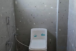 A bathroom with a toilet, a shower, and a wall-mounted sink. - Sree Mukhyaprana Residency (Mantralayam)