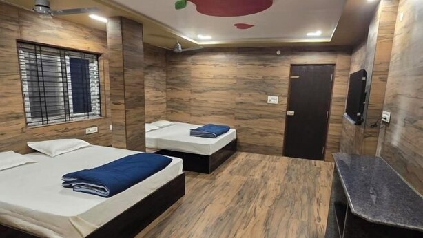 Habitación de hotel con dos camas, un escritorio pequeño y un televisor.