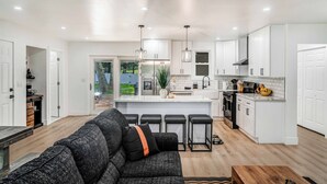 A modern kitchen with white cabinets, a central island, and bar stools. - Cozy Ranch by the Lake w/Hot Tub in the Mountains (Albrightsville)