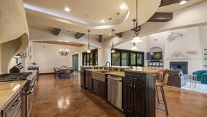 A spacious kitchen with a central island, dark cabinetry, and a large dining area with a chandelier.