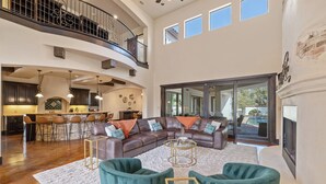 A spacious living area with a large sectional sofa, a fireplace, and a view of the outdoor pool.