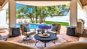 An outdoor patio with a pool, surrounded by beige furniture and a wooden ceiling.